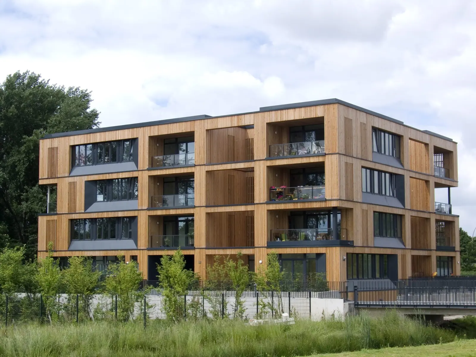 Viergeschossiges Mehrfamilienhaus mit Holzfassade und Balkonen